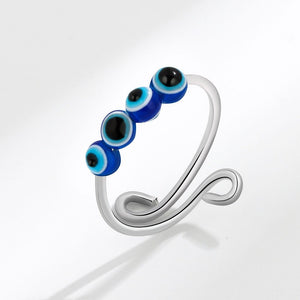 Silver spinner ring with blue and black evil eye beads on a white background
