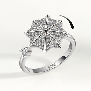 Silver ring with umbrella design and diamonds on a white background