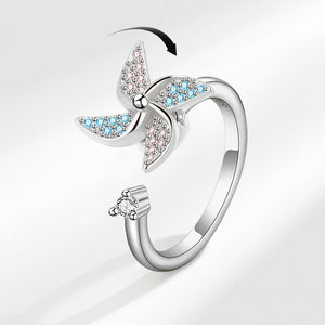 A gold-plated ring with a windmill design featuring blue cubic zirconia.